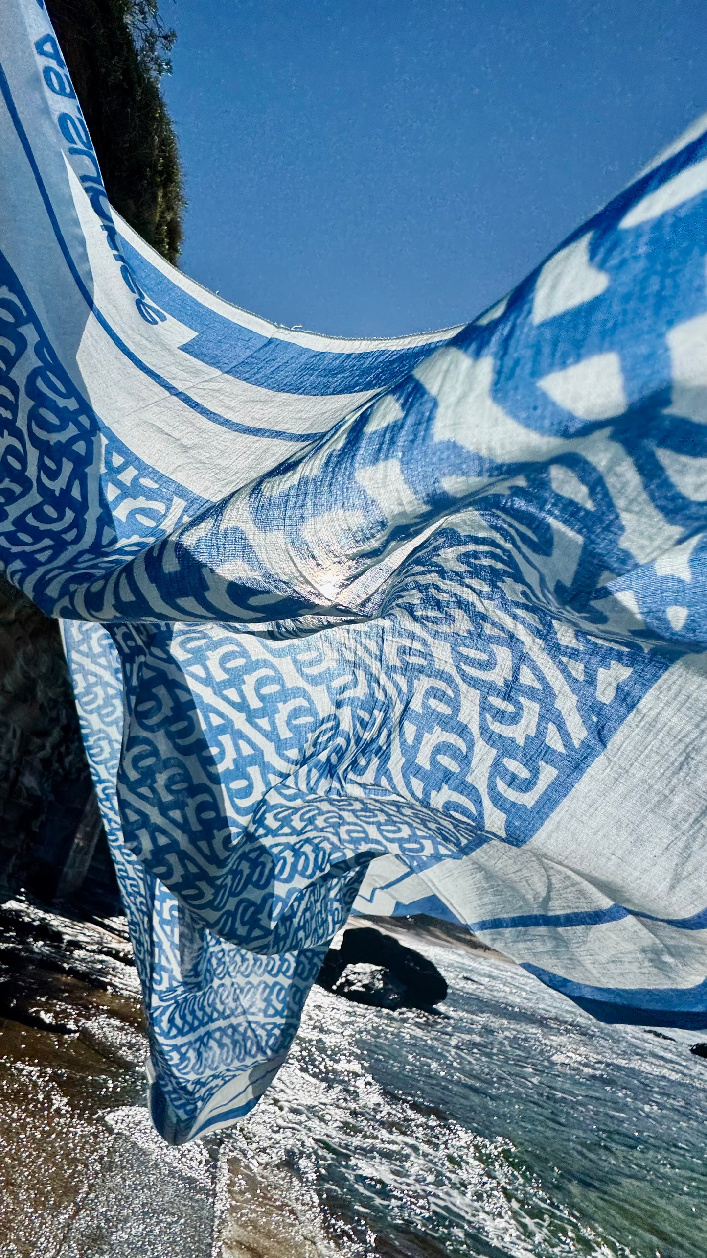 Blue and white patterned fabric draped over a natural landscape with water and rocks.