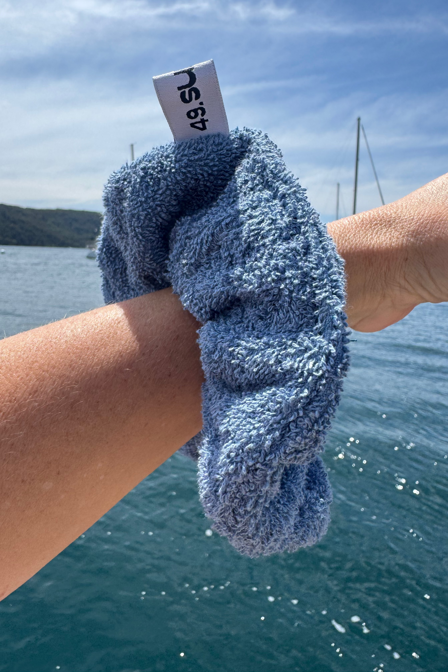 Blue towel with a tag held by a person against a scenic background