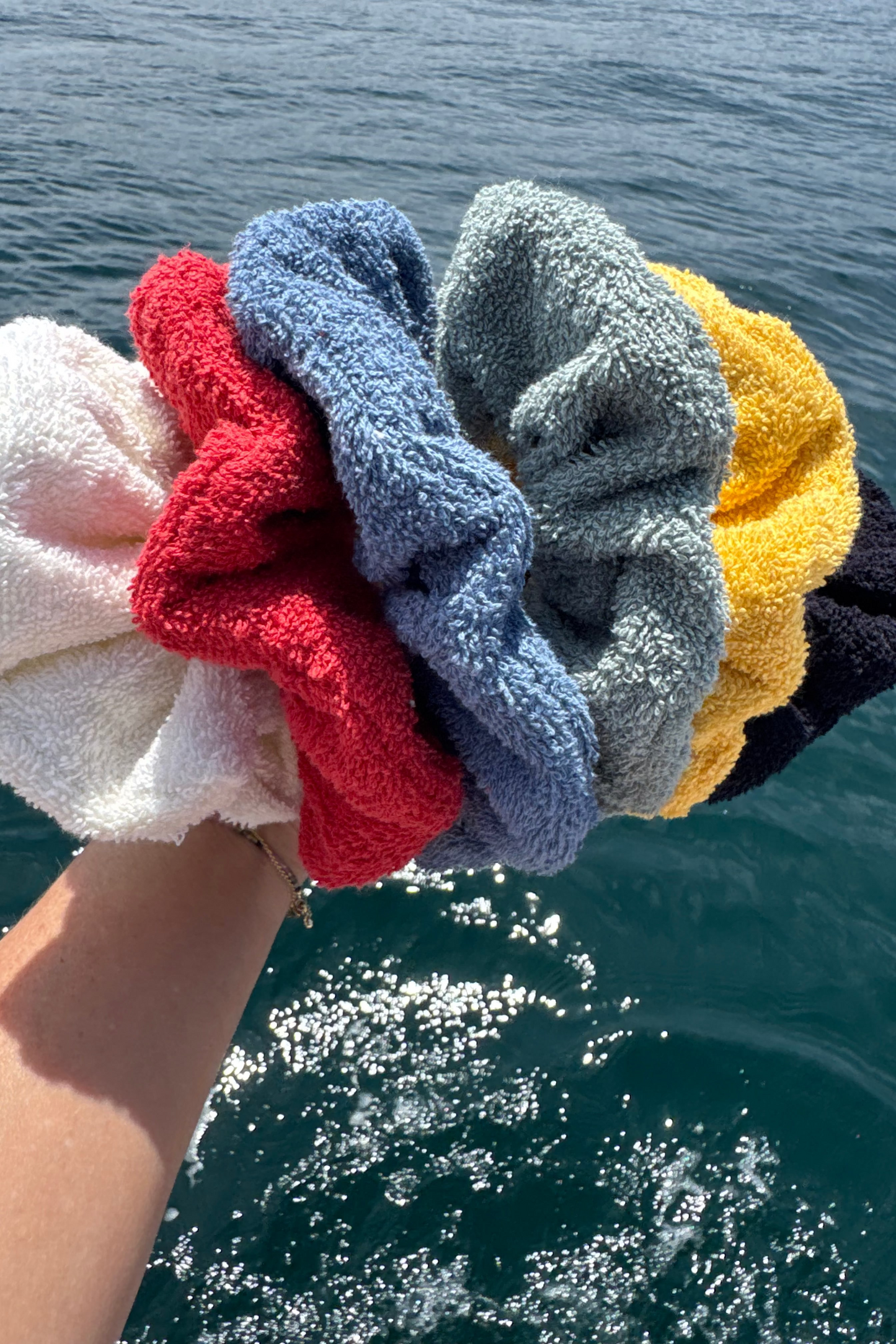 Stack of colorful scrunchies held over a body of water