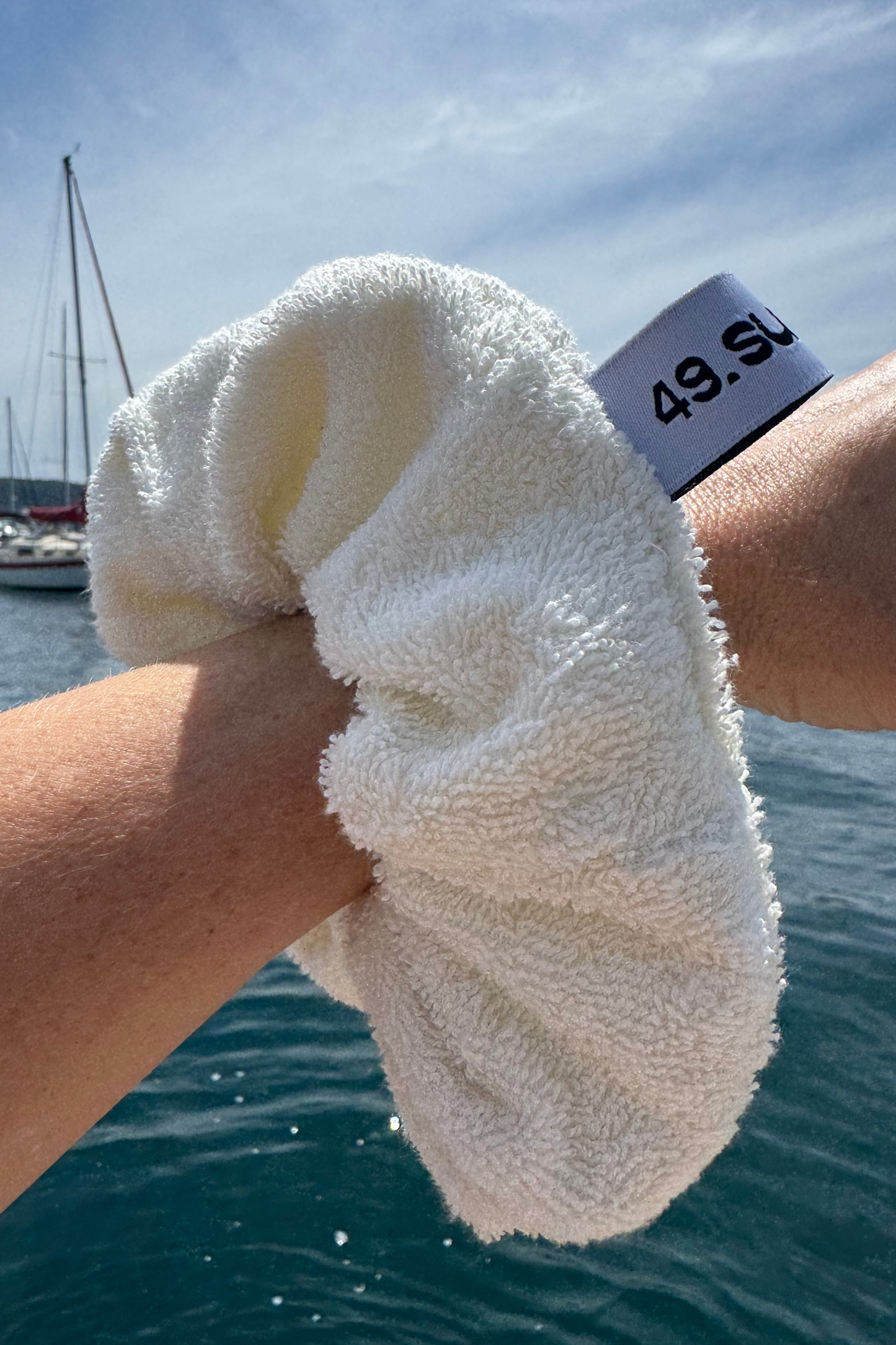 Person holding a white towel with a sailboat in the background
